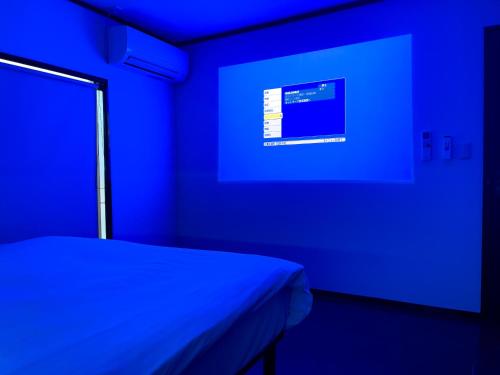 a blue room with a bed and a screen at 改装済み最大9名まで快適空間 プロジェクター付き1棟貸しの宿 こふみ in Fujikawaguchiko