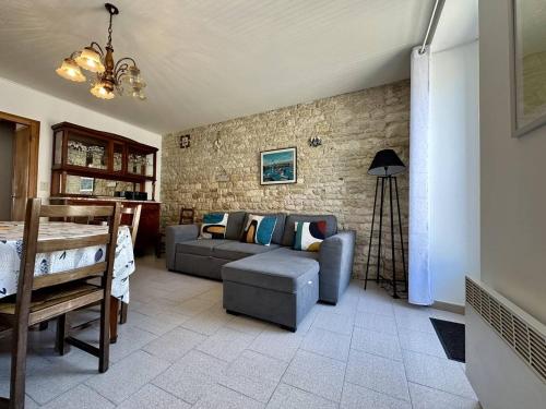 un salon avec un canapé et un mur de briques dans l'établissement Maison spacieuse à Saint-Georges-d'Oléron, 7 couchages, proche commerces, jardin et barbecue - FR-1-246A-328, à Saint-Georges-dʼOléron