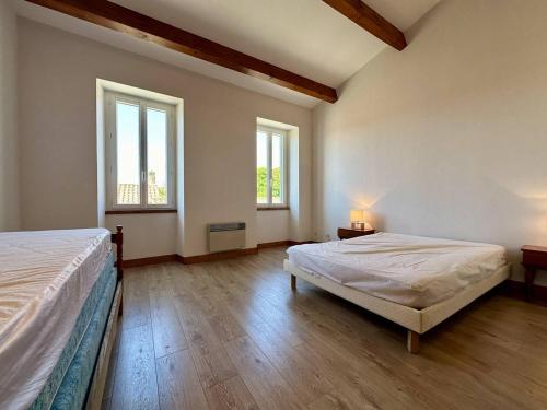 Cette grande chambre comprend deux lits et deux fenêtres. dans l'établissement Maison spacieuse à Saint-Georges-d'Oléron, 7 couchages, proche commerces, jardin et barbecue - FR-1-246A-328, à Saint-Georges-dʼOléron