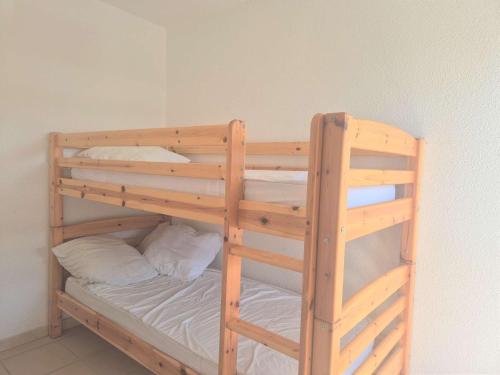- un lit superposé en bois avec des draps et des oreillers blancs dans l'établissement Appartement T2 avec terrasse et parking à 1,3 km de la plage - Cap d'Agde - FR-1-249-419, au Cap d'Agde