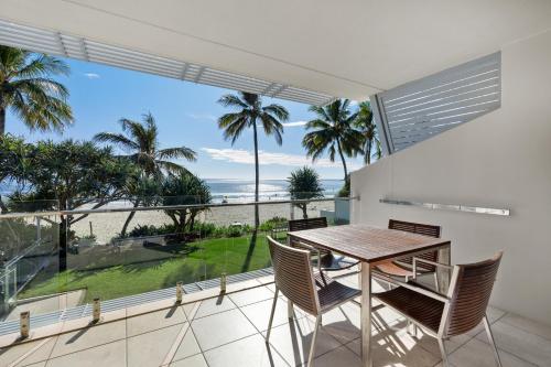 a dining room with a table and chairs and a view of the ocean at Fairshore Noosa in Noosa Heads