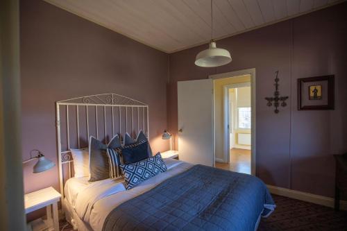 a bedroom with a large bed with blue pillows at Quince Cottage - scenic escape with spa in Daylesford