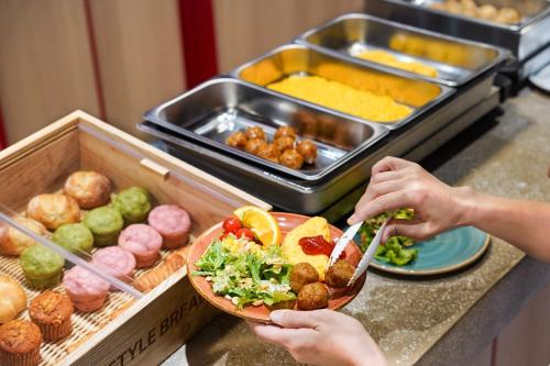 a person holding a bowl of food on a counter at lyf Ginza Tokyo in Tokyo