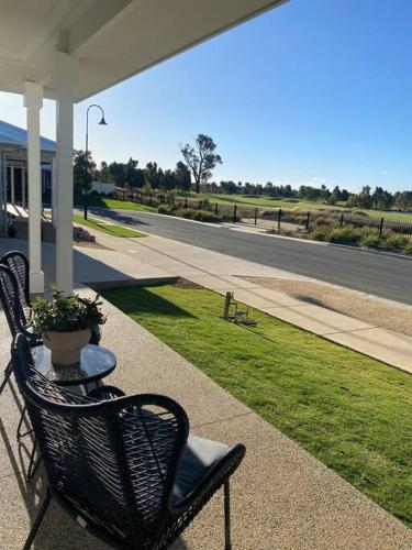 two chairs and a table with a potted plant on a porch at Brand new 4 bedroom home with Golf Views in Yarrawonga