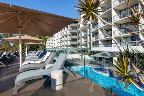 a swimming pool with lounge chairs and a hotel at Landmark Resort in Nelson Bay