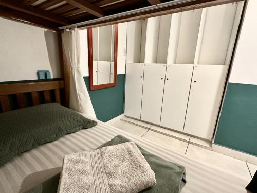 a bedroom with a bed with white cabinets and a mirror at GayFriendly Hostel BSB Airport in Brasilia