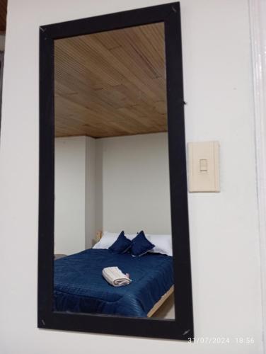 a mirror reflecting a bed in a bedroom at Hostal Camino Salinero in Zipaquirá