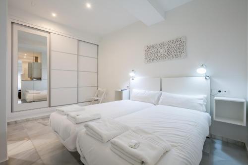 セビリアにあるSevillaHome -Apartment Castellarの白いベッドルーム(大きな白いベッド1台、鏡付)