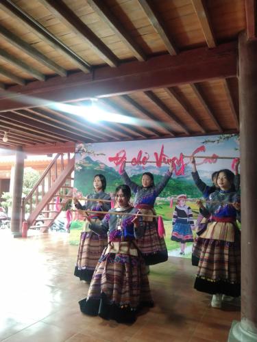 a group of girls dancing in front of a mural at A Lìn Homestay Bắc Hà in Bắc Hà