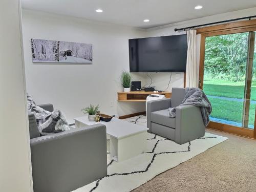 a living room with two chairs and a tv at CozyDen - AC, Grill, Bike to Mountain, Porch! in Killington