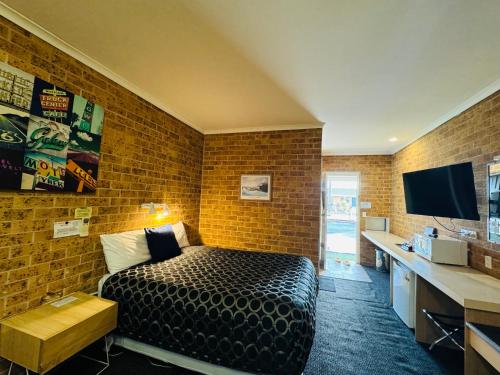 a bedroom with a bed and a brick wall at Town and Country Motor Inn in Tamworth