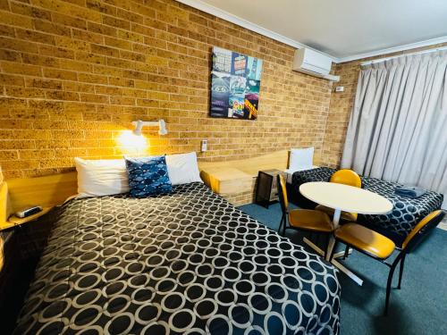 a hotel room with a bed and a table and chairs at Town and Country Motor Inn in Tamworth