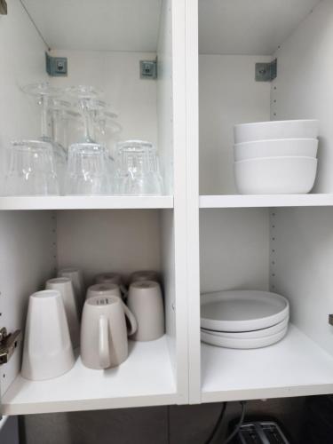 a white cabinet with dishes and cups and plates at Inverell Motel in Inverell