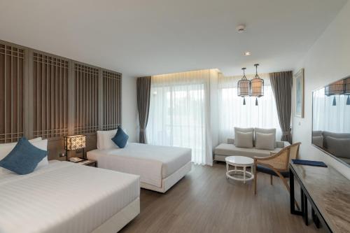 a large hotel room with two beds and a desk at Bella Nara Phuket Naiyang Beach in Nai Yang Beach