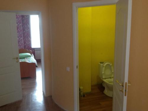 a bathroom with a toilet and a yellow wall at Holiday home Sportivnaya in Kazan