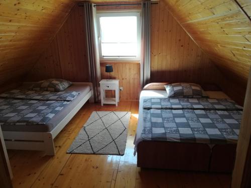 two beds in a attic room with a window at Domki Mantras in Swarzewo