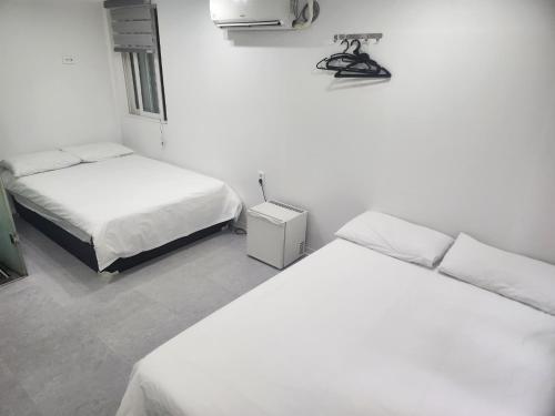 Dos camas en una habitación con paredes blancas. en K-POP Hotel Seoul Tower, en Seúl