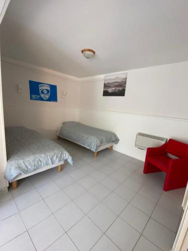 a room with two beds and a red chair at Villa "les vacances" in Les Plans