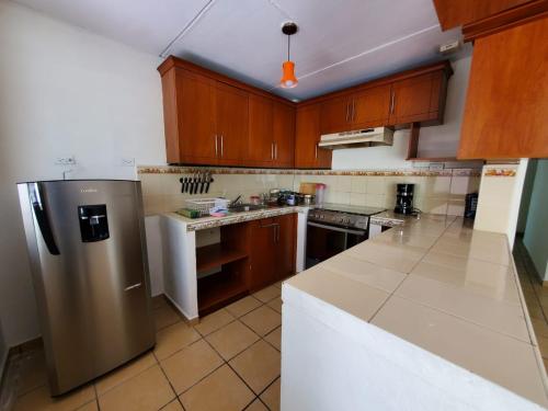 Una cocina con gabinetes de madera y un refrigerador de acero inoxidable. en Kokys Guest House, en Nueva San Salvador