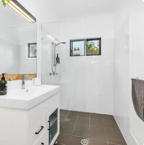a white bathroom with a sink and a shower at Studio 37 Byron Bay in Byron Bay