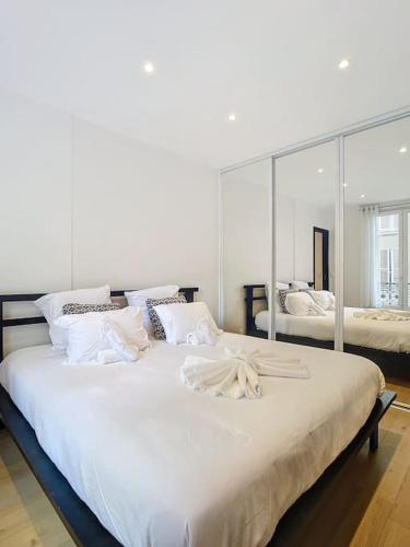- une chambre avec un grand lit blanc et un grand miroir dans l'établissement Studio 49-Le Cocon-Métro à 1mn, à Paris