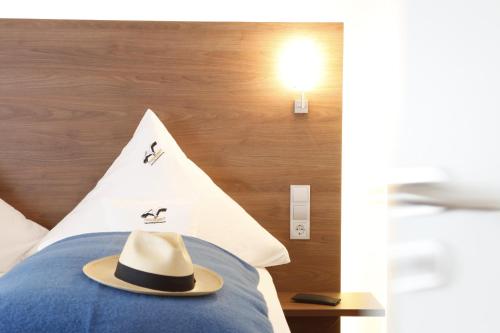 a hat on top of a bed with a wall at Bodensee Hotel Storchen in Uhldingen-Mühlhofen