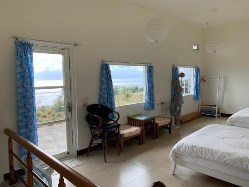 a bedroom with a bed and two windows at 海闊天空 丁一的家民宿 Pacific Ocean View in Chenggong