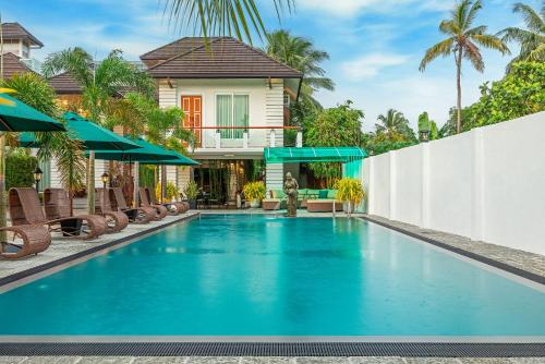 a pool with chairs and umbrellas in front of a house at The Palace by Ocean in Bentota