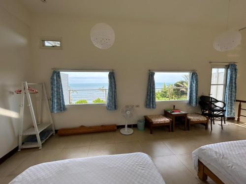 a bedroom with two windows and a table and chairs at 海闊天空 丁一的家民宿 Pacific Ocean View in Chenggong