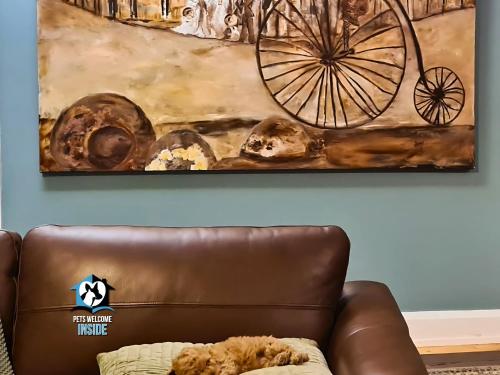 a brown leather couch with a painting on the wall at 3 BR Little Addis Cottage in Historic Kalgoorlie in Kalgoorlie