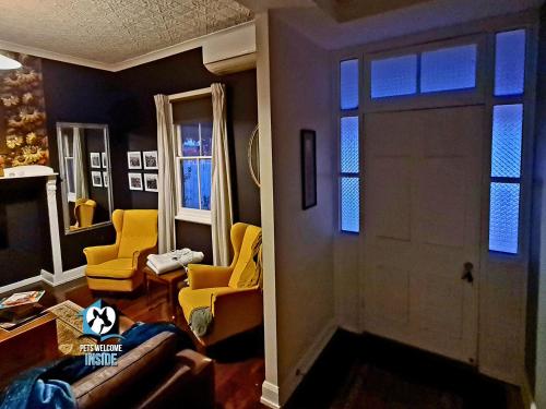 a living room with yellow chairs and a door at 3 BR Little Addis Cottage in Historic Kalgoorlie in Kalgoorlie