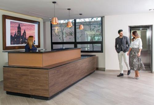 a man and a woman standing in a lobby at Staybridge Suites - Guadalajara Novena by IHG in Guadalajara