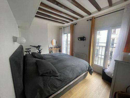 une chambre avec un lit et une grande fenêtre dans l'établissement APPAREMMENT Familiale Centre Paris 3ch 3SDB, à Paris