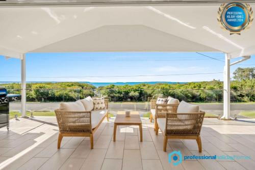 a patio with a white canopy and chairs and a table at Callala Beach Walk - Beachfront with Fireplace in Callala Beach