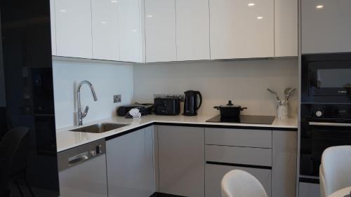 a kitchen with white cabinets and a sink and a microwave at Panorama Suite Hotel in Iskele