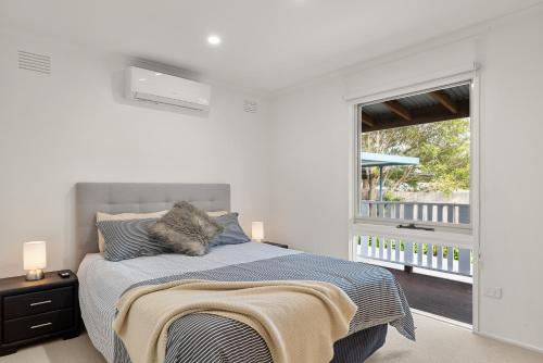 a white bedroom with a bed and a large window at Retreat on Red Rocks in Cowes