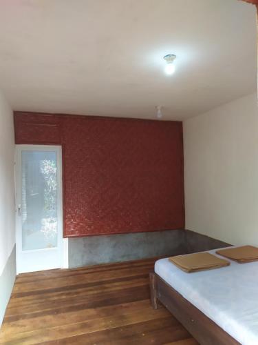 a room with a bed and a red wall at Happy Monkeys Village in Sidomukti