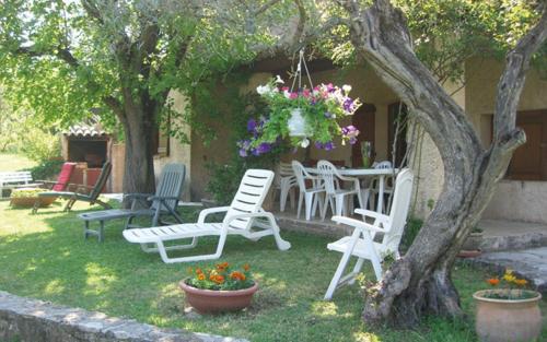 a yard with chairs and a table with flowers at Gite lefevre a callian in Callian