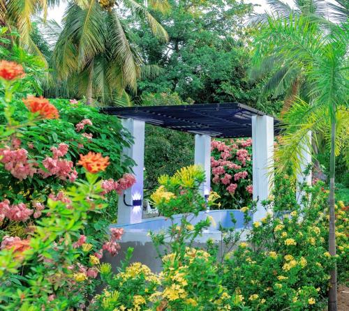 a garden with colorful flowers and a black canopy at Villa Exora Pasikudha in Batticaloa