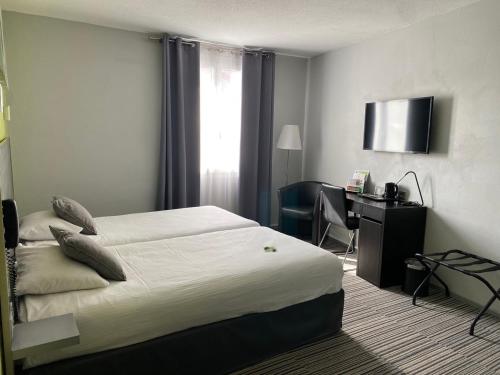 a hotel room with a bed and a desk at Hôtel Bagatelle in Pont-à-Mousson