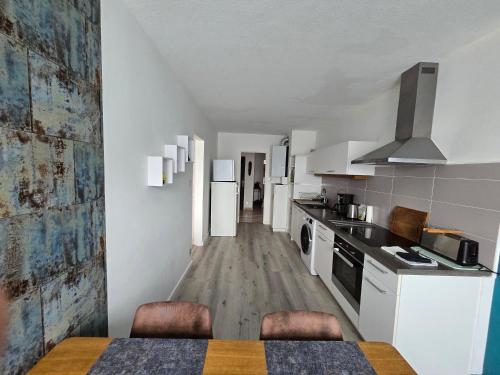 - une cuisine avec des appareils blancs, une table et des chaises dans l'établissement Bel appartement 3 pièces dans une résidence calme, à Sélestat
