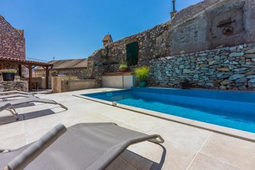 a swimming pool in front of a stone building at Casa Royal in Bribir