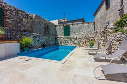 a patio with a swimming pool next to a stone wall at Casa Royal in Bribir