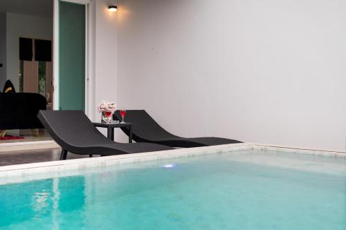 a swimming pool with two chairs and a table at Nariya Bayfront Phuket in Ban Bang Chak