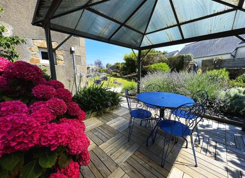 a patio with a blue table and chairs and flowers at Maison Les Agapanthes. in Lanmodez