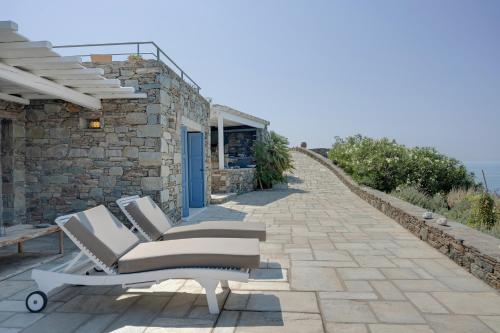 a patio with two lounge chairs and a building at Blueros Luxury Villa in Megas Yialos-Nites