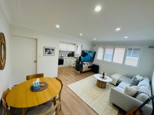 a living room with a couch and a table at Coogee Sunrise 2 Bed Apt with Parking, Work Desks & Balcony in Sydney