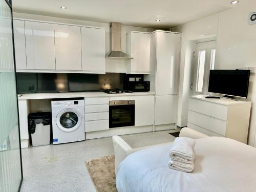 a kitchen with white cabinets and a washer and dryer at Westferry Two-Bedroom Deluxe Apartment in London