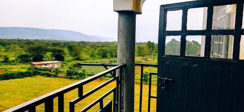 a door to a balcony with a view of a field at Vee's 1br Apartment at Lower Section 58 with Lakeviews in Nakuru