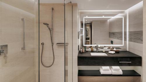 a bathroom with a shower and a sink and a mirror at Hilton Munich Airport in Oberding